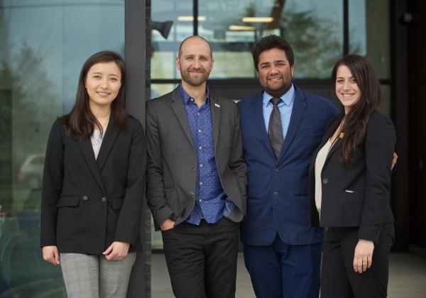 Four MBA students in business attire standing together for a photo