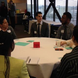 A group of students and employers talking at a table during the LMRT