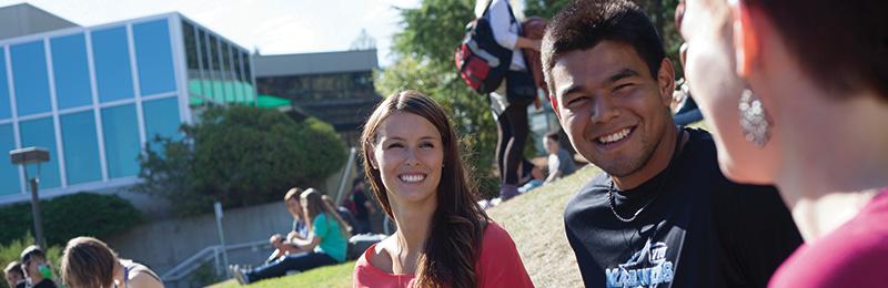 VIU students sitting on grass in the summer at Nanaimo campus