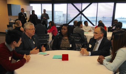 A group of students and employers talking at a table during the LMRT